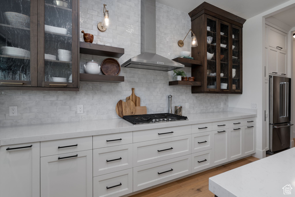 Kitchen with wall chimney range hood, stainless steel appliances, open shelves, and backsplash