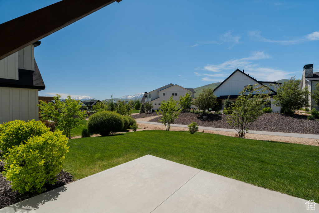 View of grassy yard with a patio area and a residential view