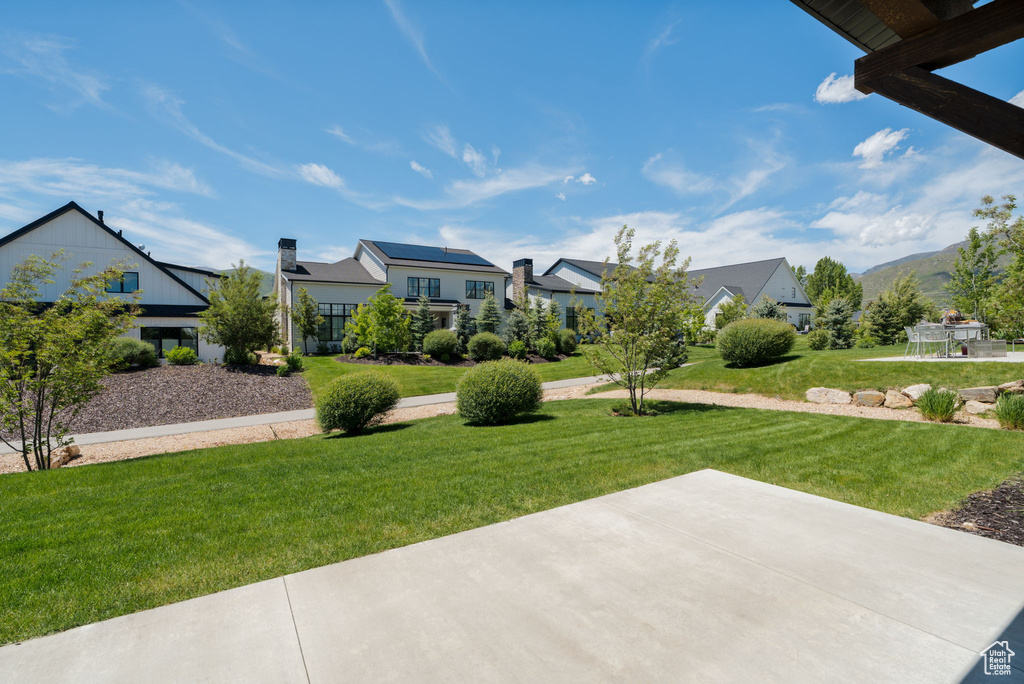 View of green lawn featuring a patio area and a residential view