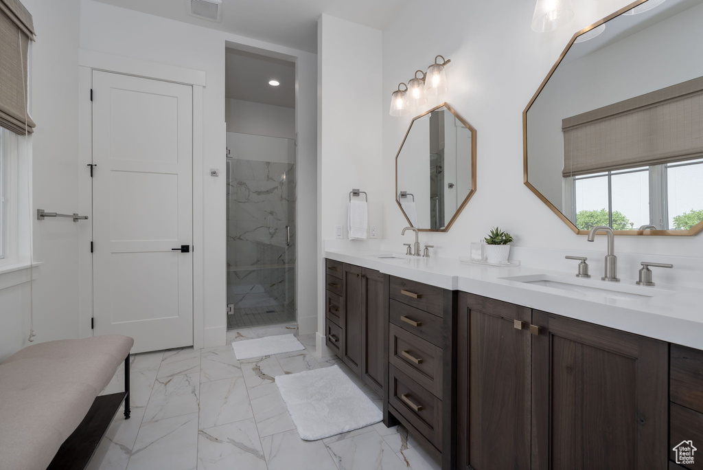 Bathroom with marble look tiles, double vanity, a marble finish shower, and recessed lighting