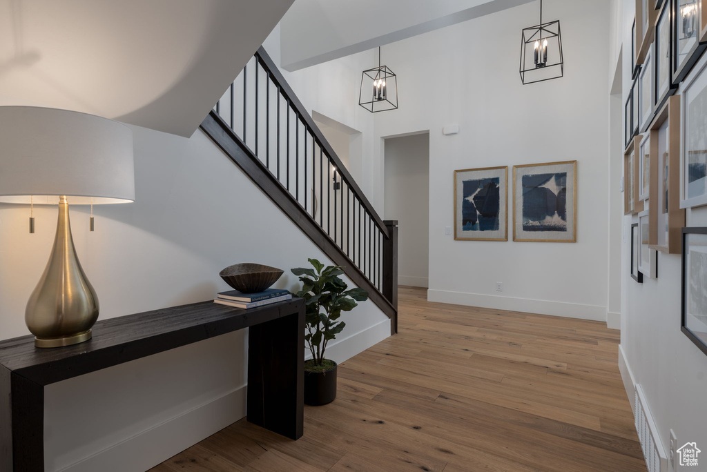 Foyer entrance with wood finished floors, baseboards, stairs, a towering ceiling, and a chandelier