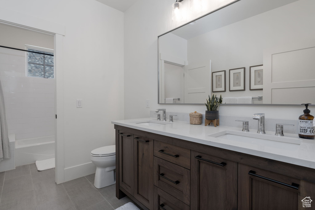 Bathroom with toilet, double vanity, bathtub / shower combination, and tile patterned floors
