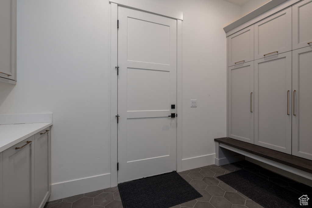 Mudroom featuring dark tile patterned floors and baseboards