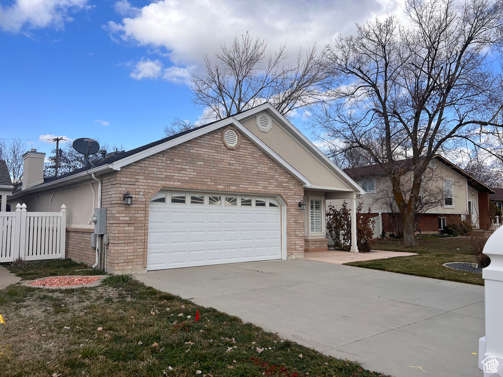 Ranch-style home with brick siding, concrete driveway, a garage, and a chimney