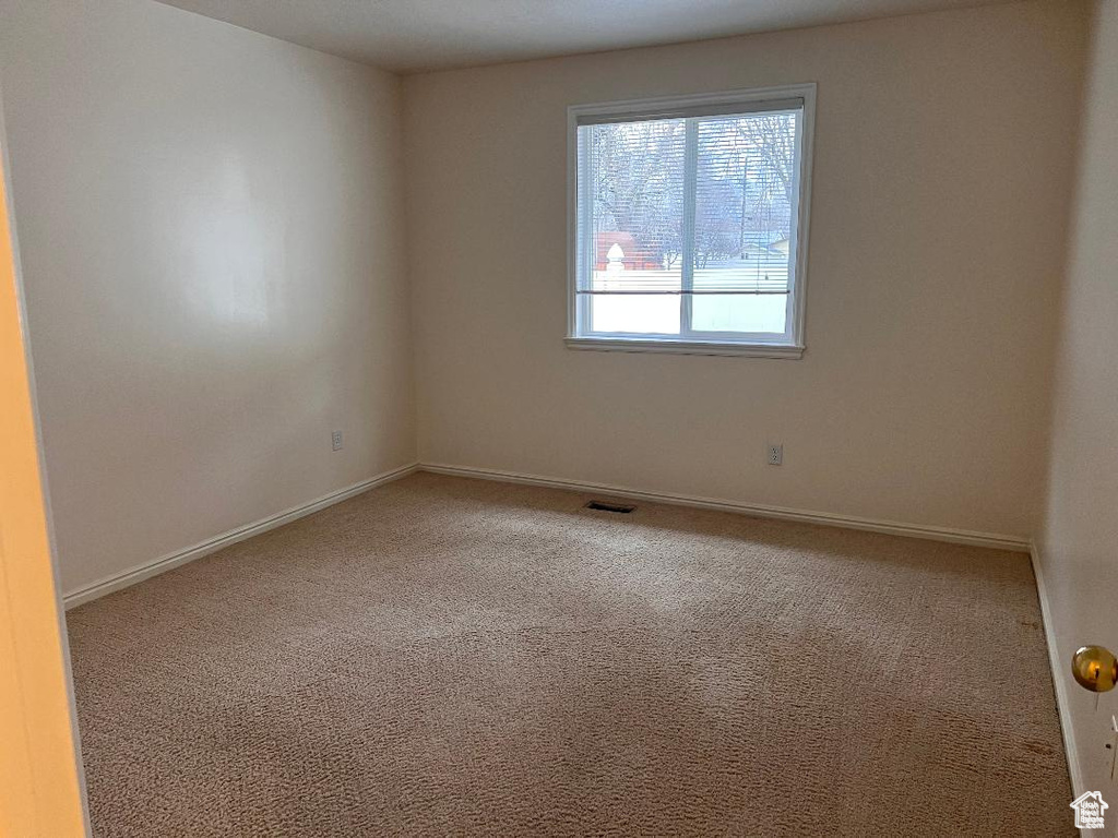 Spare room featuring carpet and baseboards