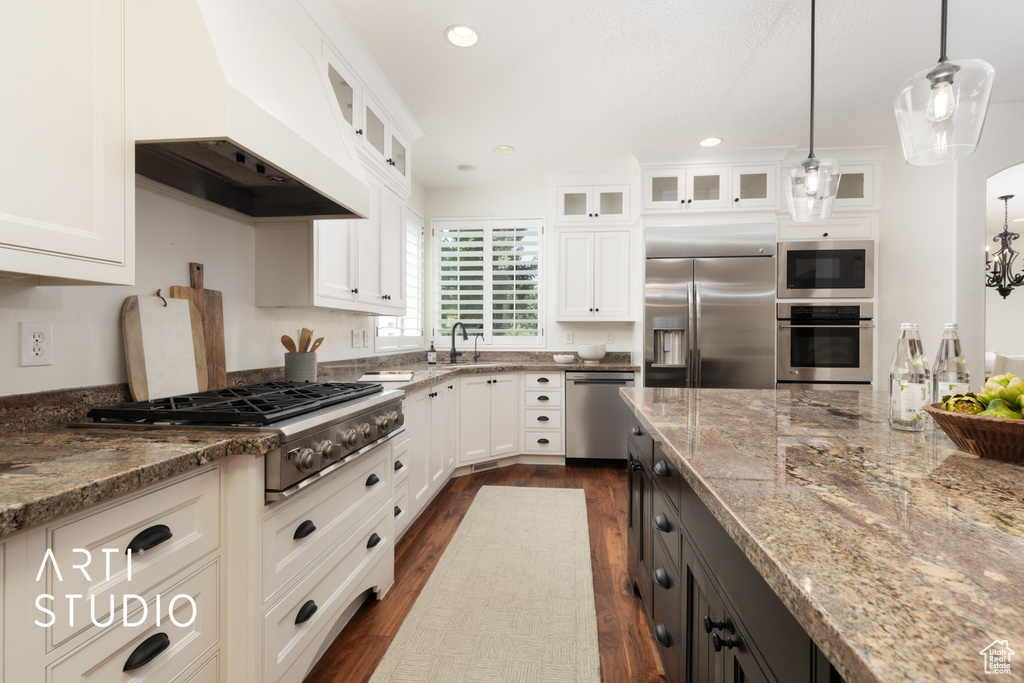 Kitchen featuring appliances with stainless steel finishes, custom range hood, dark wood-style flooring, light stone countertops, and recessed lighting