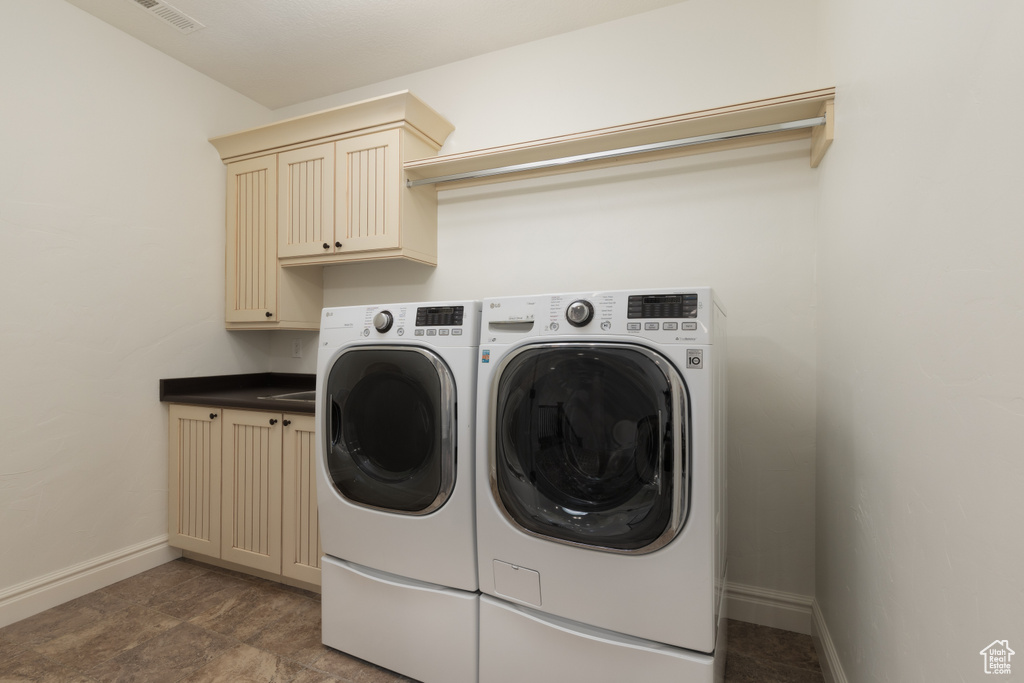 Laundry area with washer and clothes dryer, cabinet space, and baseboards