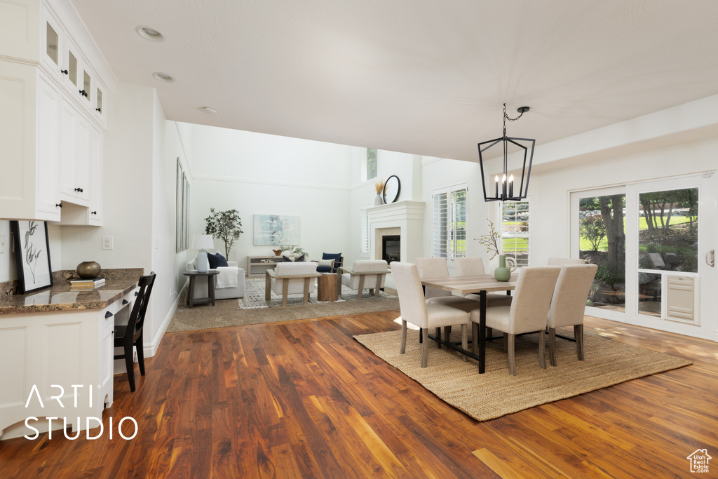 Dining room with dark wood-type flooring, a glass covered fireplace, a chandelier, and recessed lighting