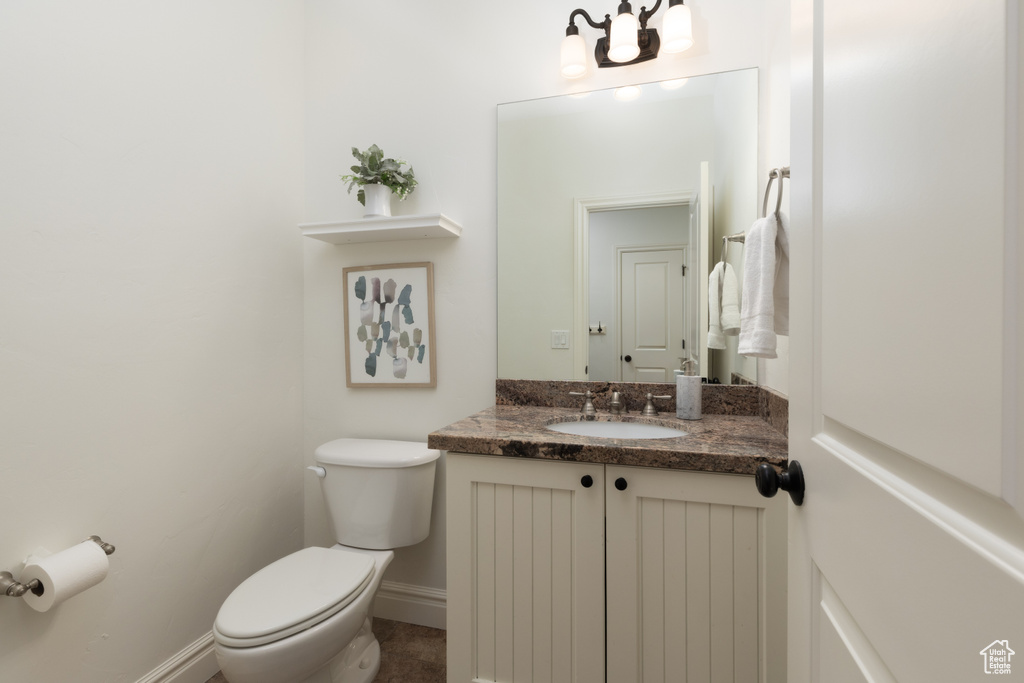 Bathroom with toilet, vanity, baseboards, and a chandelier