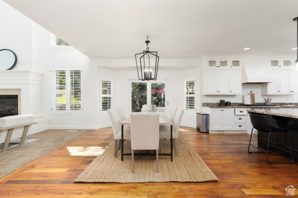 Dining area featuring a chandelier, dark wood finished floors, recessed lighting, a glass covered fireplace, and baseboards