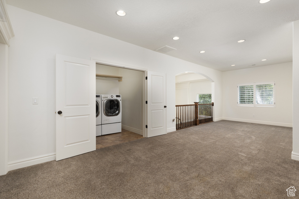 Carpeted empty room with separate washer and dryer, arched walkways, recessed lighting, and baseboards