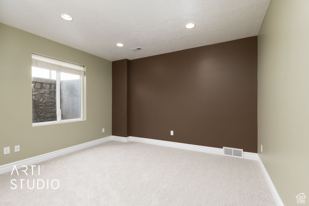 Empty room featuring light carpet, baseboards, recessed lighting, and a textured ceiling