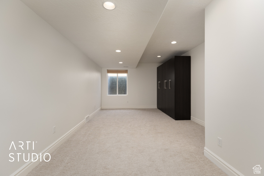 Spare room featuring recessed lighting, light carpet, and baseboards