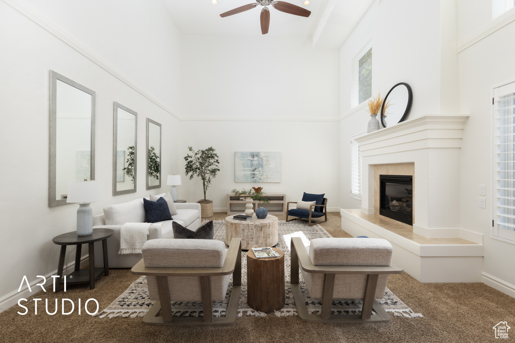 Living area featuring a towering ceiling, a ceiling fan, a premium fireplace, and carpet flooring