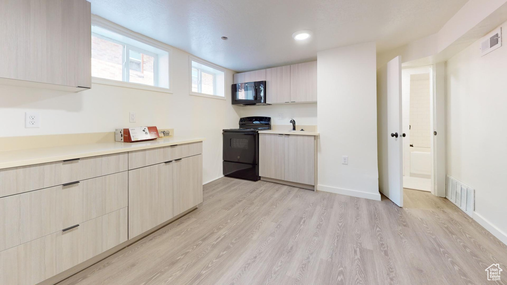 Kitchen featuring black appliances, light countertops, modern cabinets, and recessed lighting
