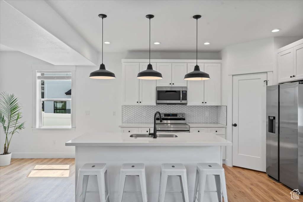 Kitchen featuring appliances with stainless steel finishes, a sink, light wood-style flooring, light countertops, and recessed lighting