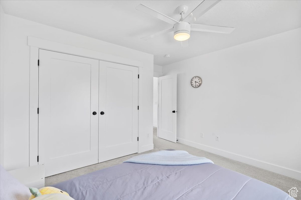 Bedroom with baseboards, a closet, ceiling fan, and light colored carpet