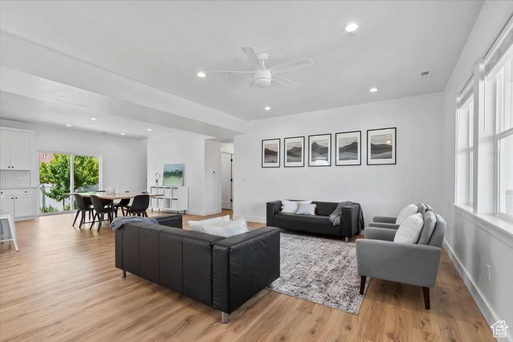 Living room with light wood-type flooring, a ceiling fan, recessed lighting, and baseboards