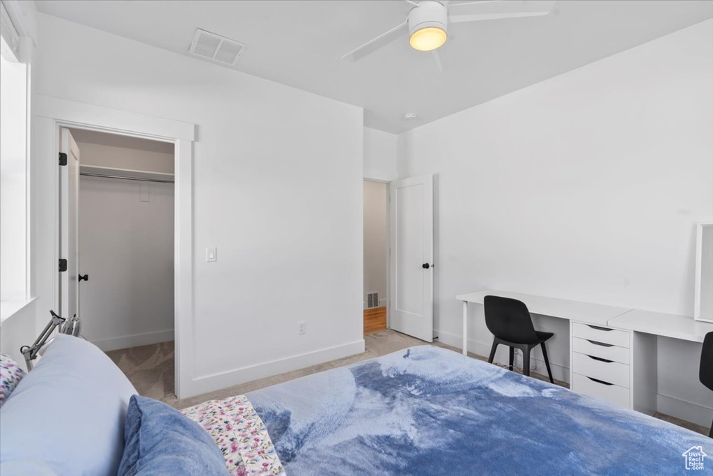 Bedroom with a desk, a walk in closet, baseboards, and a ceiling fan