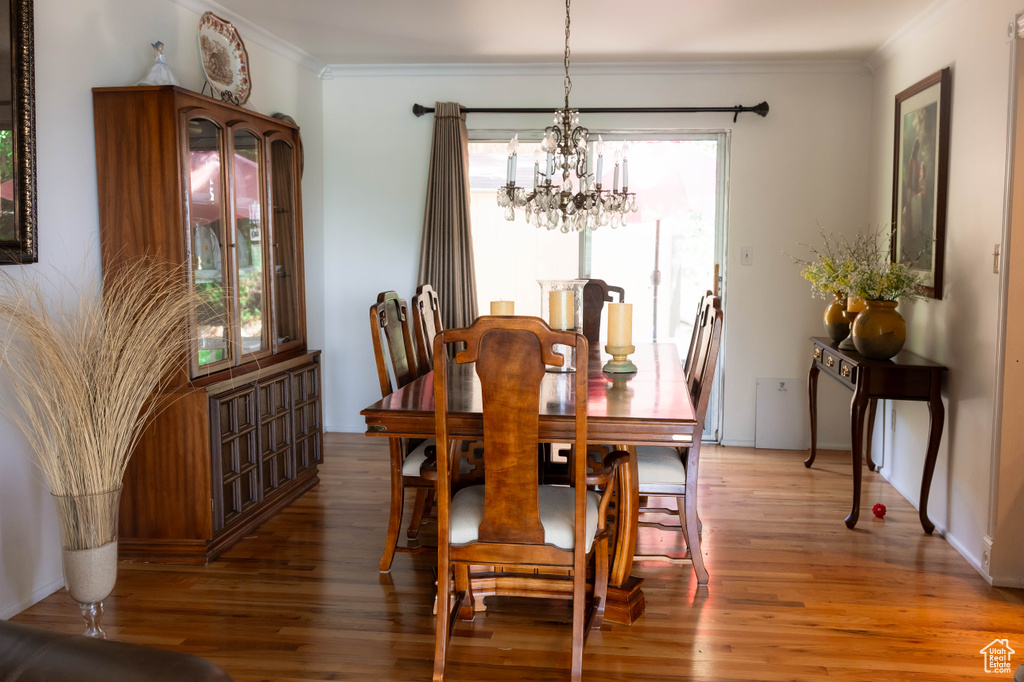 Dining area featuring a chandelier, healthy amount of natural light, light wood-type flooring, and ornamental molding