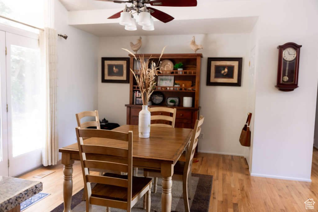 Dining room with light wood finished floors, a ceiling fan, and baseboards