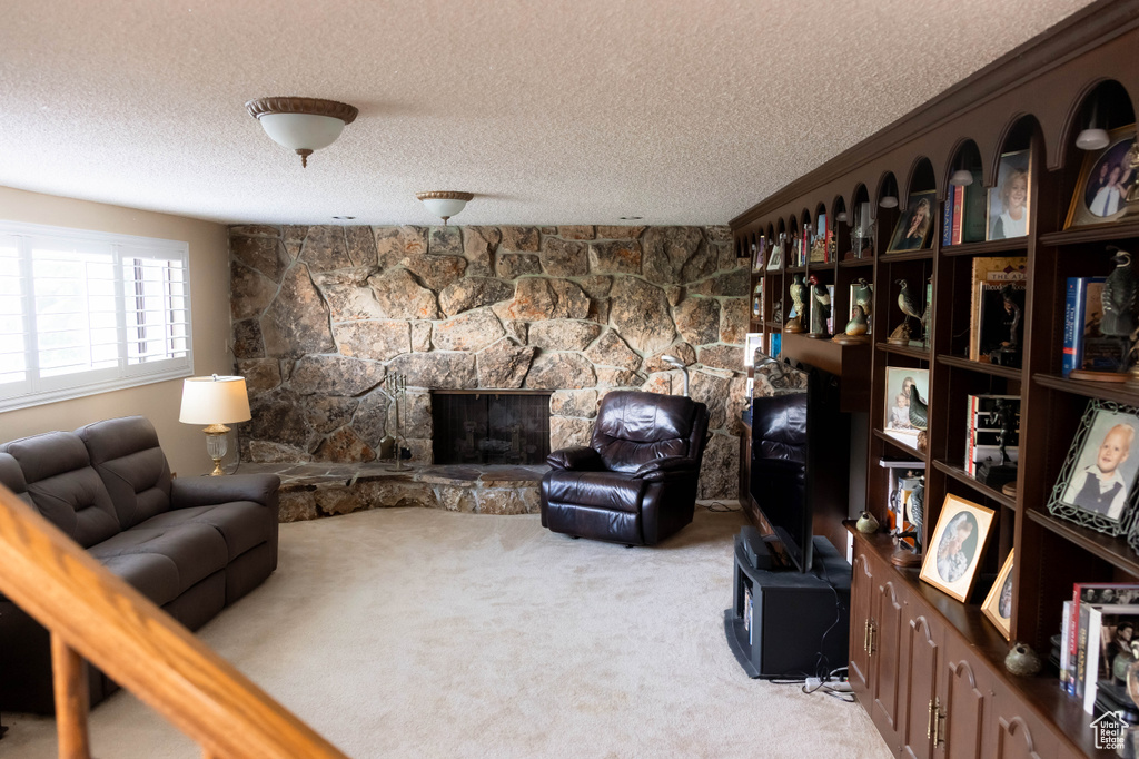 Carpeted living room with a textured ceiling and a stone fireplace