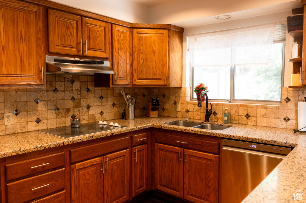 Kitchen featuring dishwasher, a sink, under cabinet range hood, black electric stovetop, and decorative backsplash