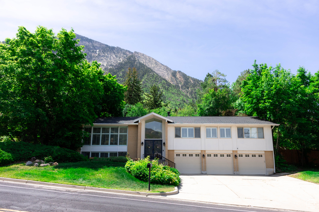 Split foyer home with concrete driveway, an attached garage, a mountain view, and brick siding