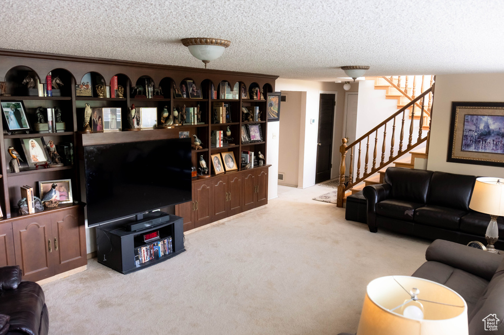 Living room with carpet flooring, stairs, and a textured ceiling