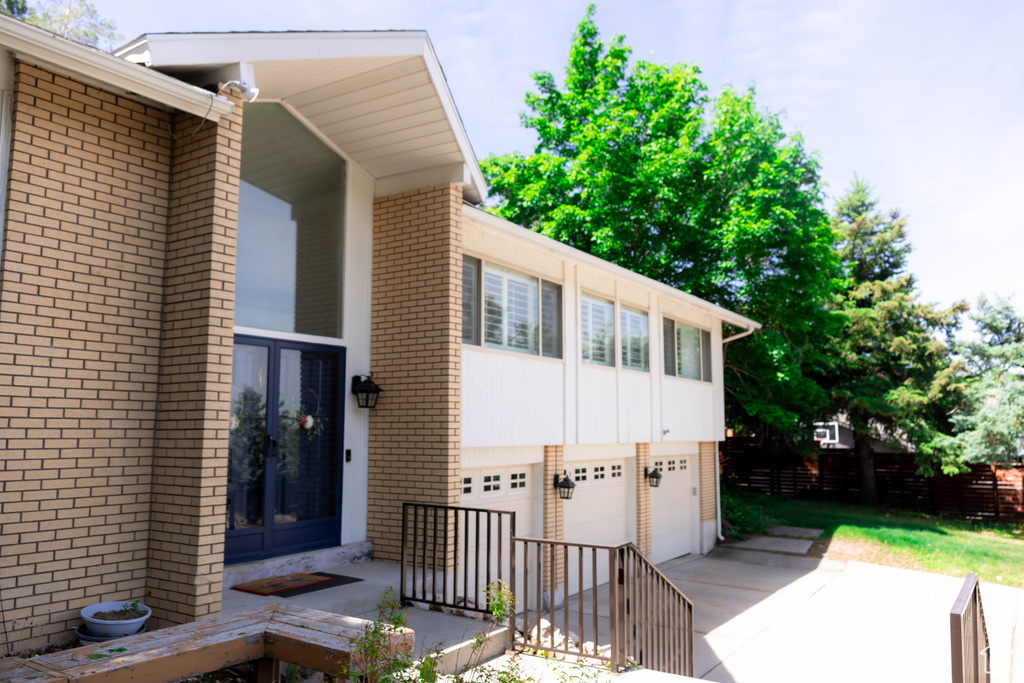Property entrance with brick siding, a garage, concrete driveway, and french doors