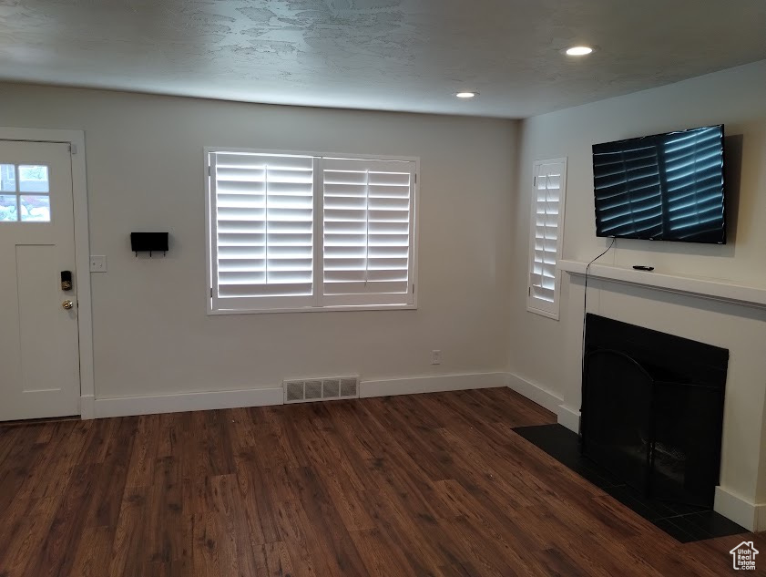 Unfurnished living room featuring wood finished floors, a fireplace with flush hearth, recessed lighting, and baseboards