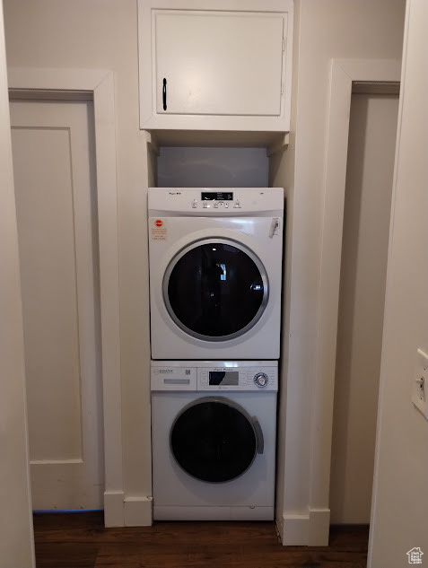 Washroom featuring stacked washer / dryer and dark wood finished floors