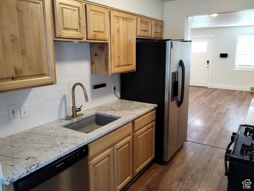 Kitchen with a sink, stainless steel appliances, decorative backsplash, and dark wood-type flooring