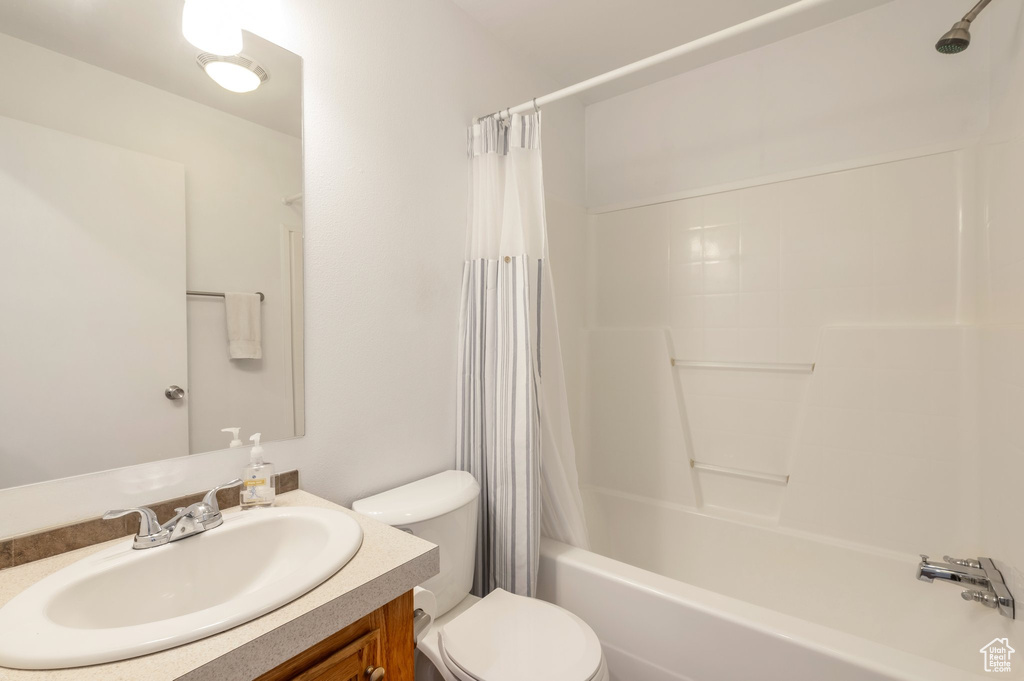 Bathroom featuring vanity, shower / bath combo with shower curtain, and toilet