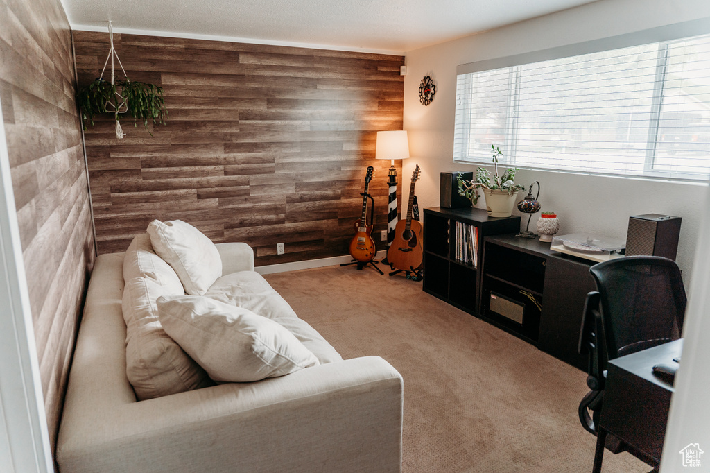 Living room with carpet floors, an office area, wood walls, and tile walls
