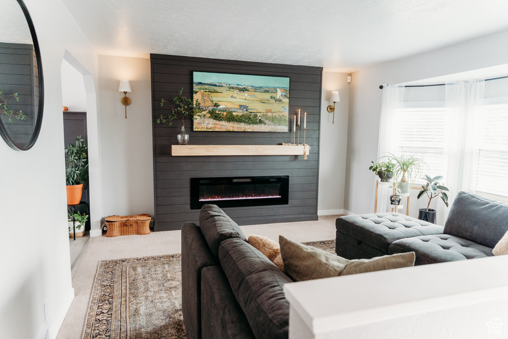 Carpeted living area featuring a large fireplace and baseboards