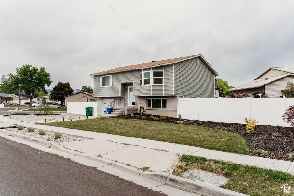 Split foyer home with a garage, brick siding, and concrete driveway