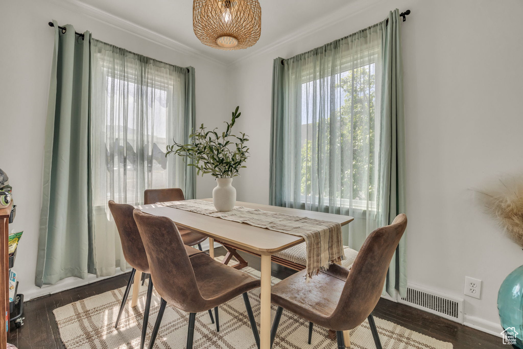 Dining area with healthy amount of natural light, crown molding, wood finished floors, and baseboards