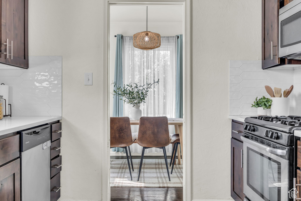 Kitchen featuring stainless steel appliances, decorative backsplash, light countertops, and dark brown cabinets