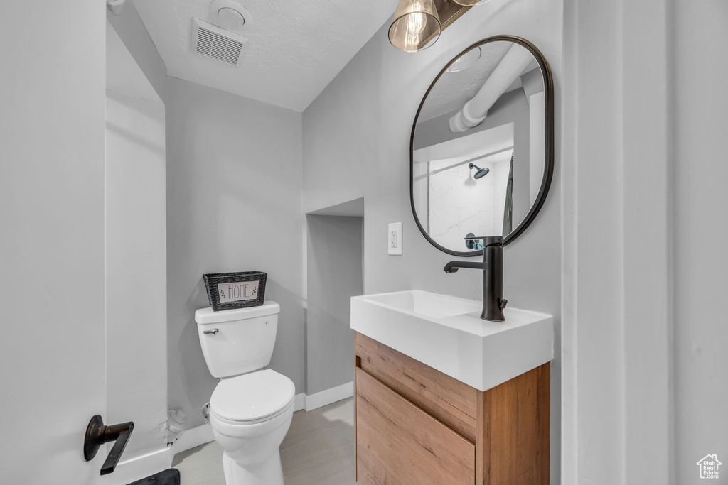 Bathroom with toilet, vanity, and baseboards