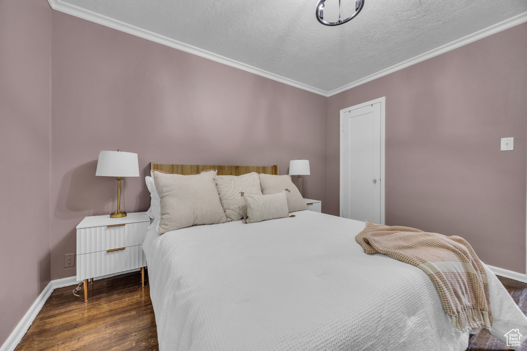 Bedroom with wood finished floors, ornamental molding, baseboards, and a textured ceiling
