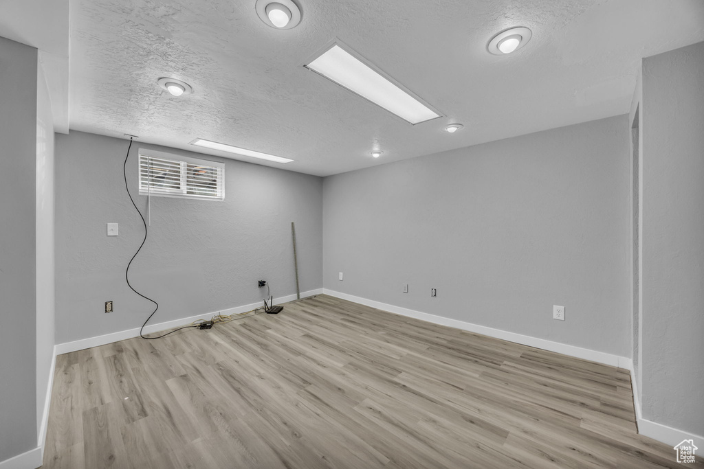 Basement featuring wood finished floors, baseboards, and a textured ceiling