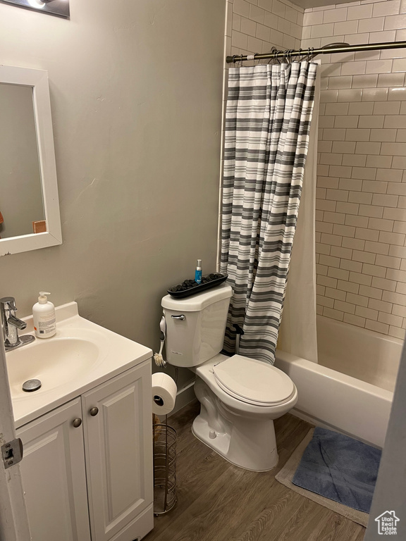 Bathroom with toilet, vanity, shower / tub combo, and wood finished floors