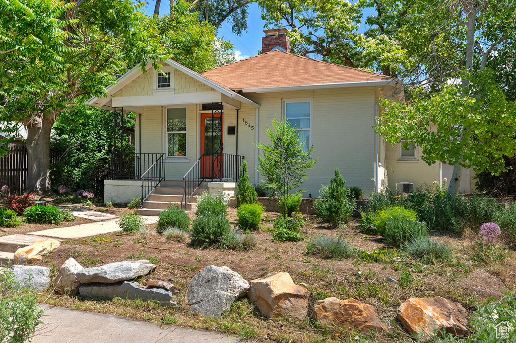 Bungalow-style home with a chimney, covered porch, and central AC