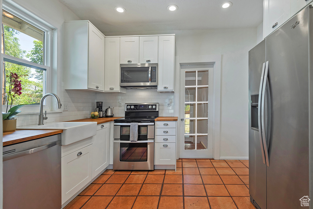 Kitchen featuring appliances with stainless steel finishes, a sink, backsplash, recessed lighting, and white cabinets