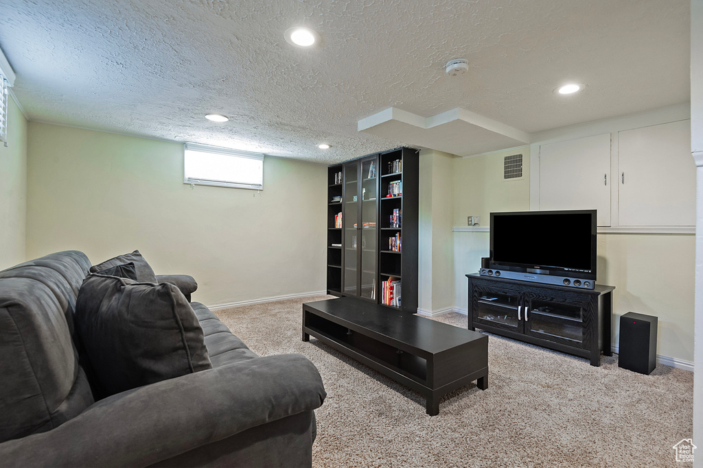 Living area with a textured ceiling, baseboards, carpet floors, and recessed lighting