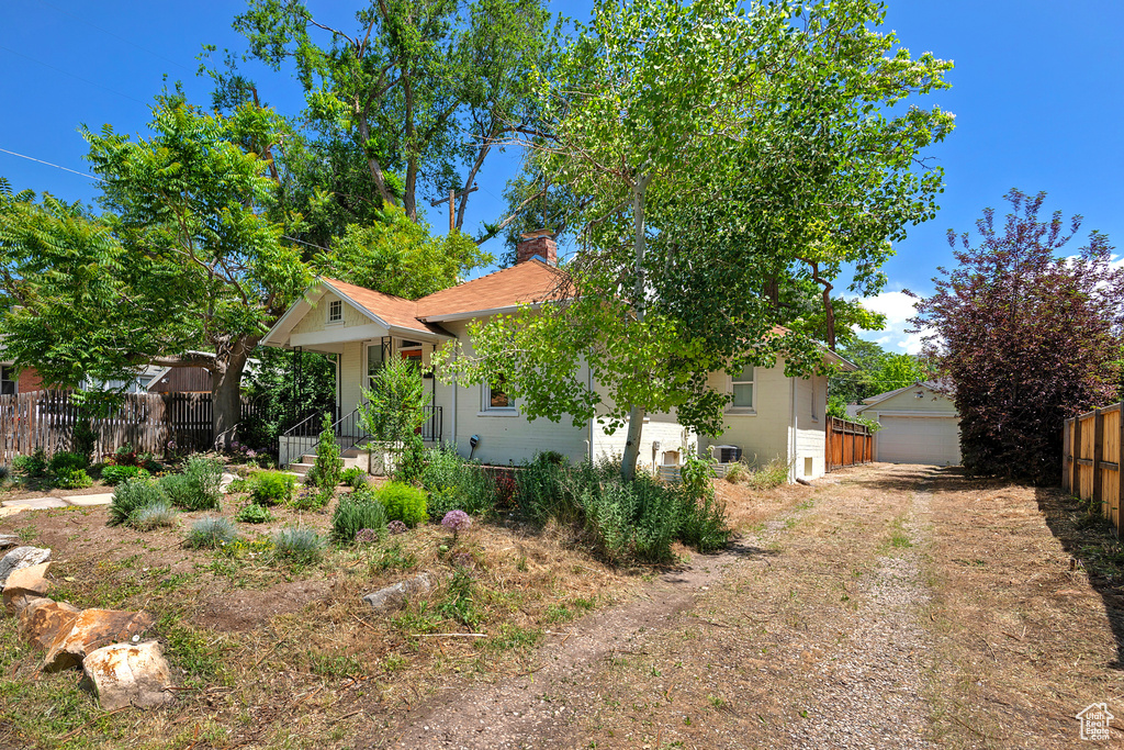 View of front of house featuring a chimney, an outbuilding, and a detached garage
