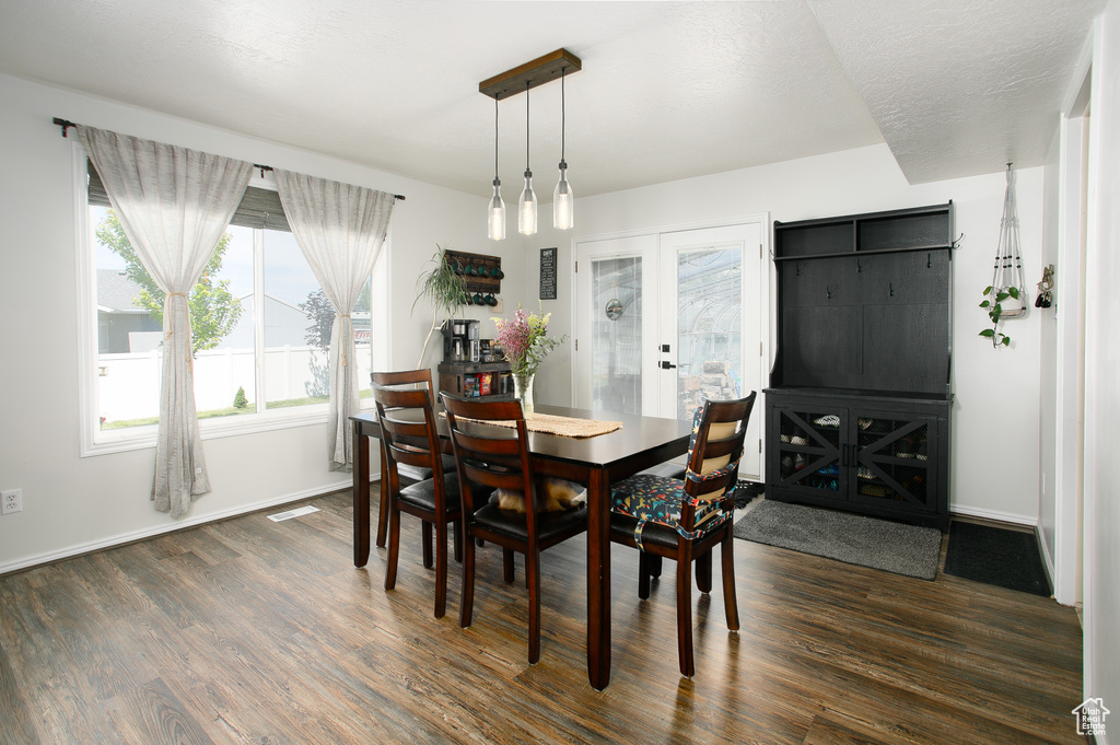 Dining room with dark wood-type flooring, baseboards, and french doors