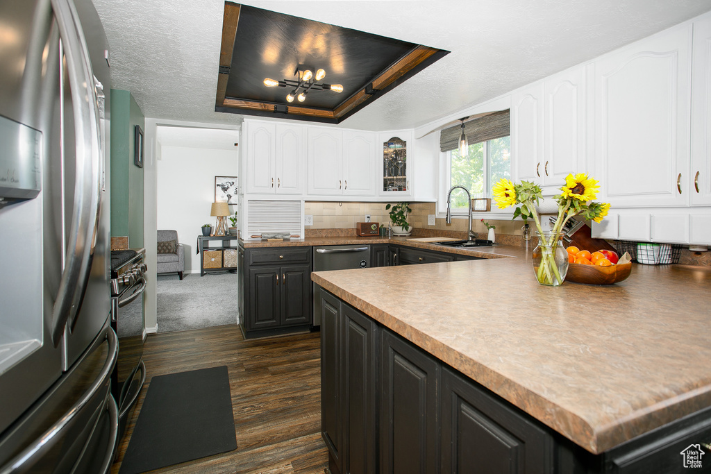 Kitchen featuring appliances with stainless steel finishes, a sink, white cabinets, and dark wood-style flooring