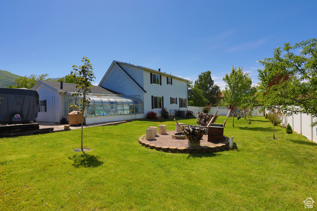 View of yard featuring a sunroom, a fire pit, and a patio
